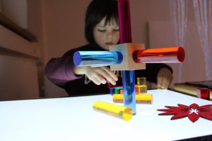 Ein Kind sitzt an einem Tisch und beschäftigt sich mit bunten Gegenständen. Ein Kind sitzt an einem Tisch und beschäftigt sich mit bunten Gegenständen.